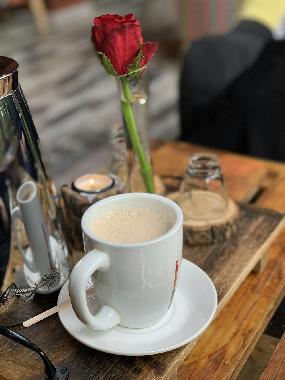 coffee in mug on saucer beside red rose