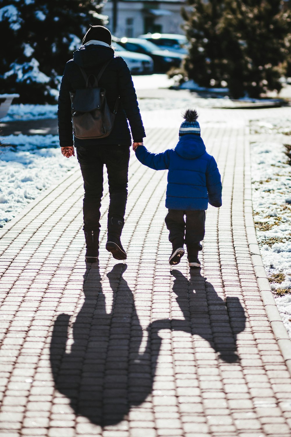 person in black jacket holding hand with toddler