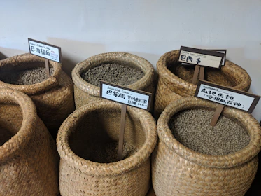 Artisan arranging freshly harvested coffee beans and spices in woven baskets.