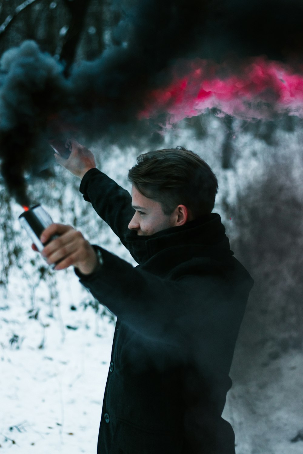 man wearing black jacket holding smoking cans