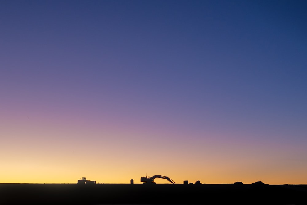 silhouette of excavator against yellow light