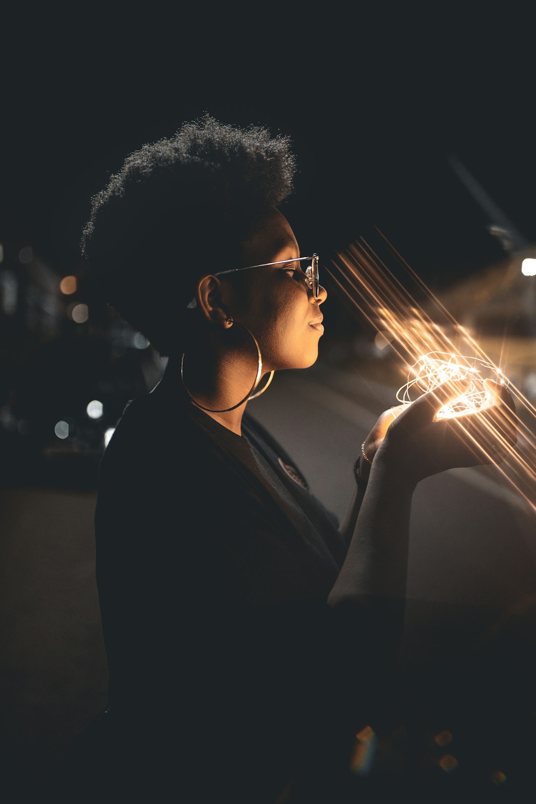 woman standing and holding string lights