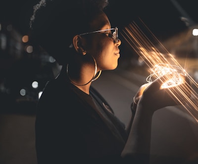 woman standing and holding string lights