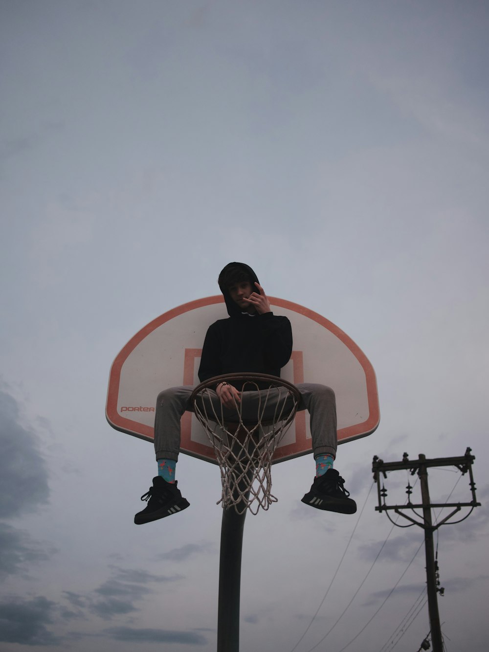 man sitting on red and white basketball hoop