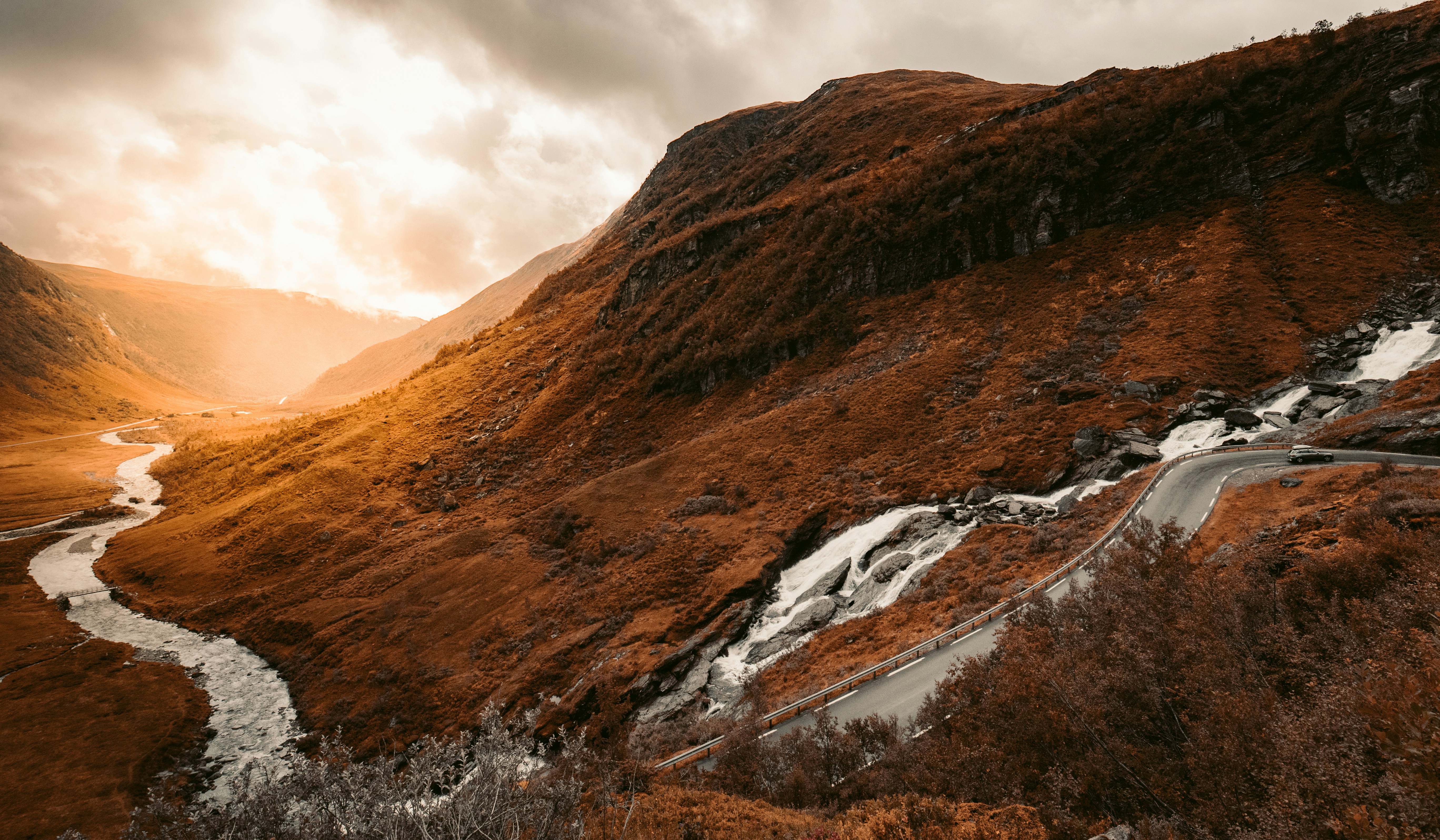 Scenic mountain road trip route through valley at sunset in Norway