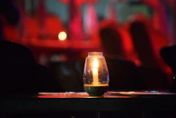 Glass candle stands glowing softly on a wooden table during evening light.