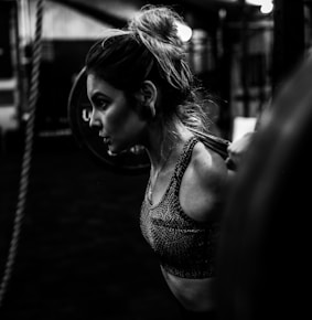 greyscale photo of woman in bralette inside room