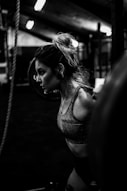 greyscale photo of woman in bralette inside room