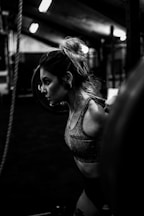 greyscale photo of woman in bralette inside room