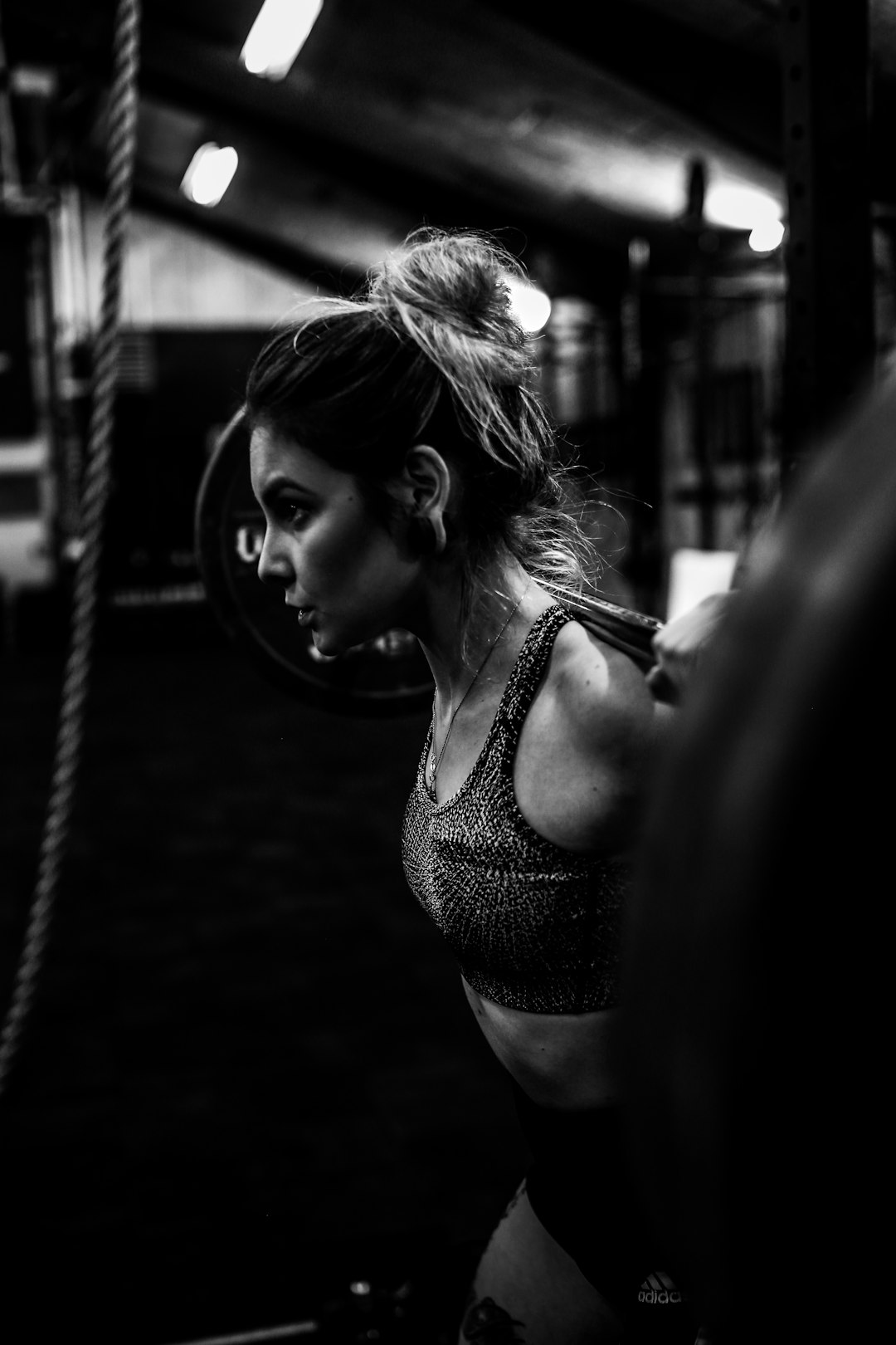 greyscale photo of woman in bralette inside room