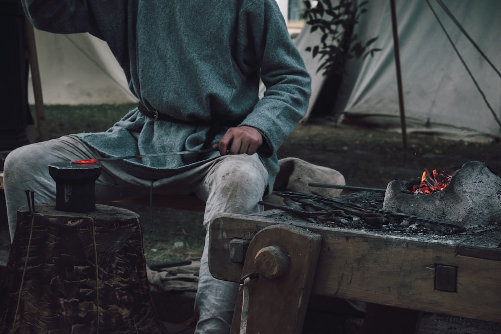 persona in camicia grigia che si siede sulla panca di legno