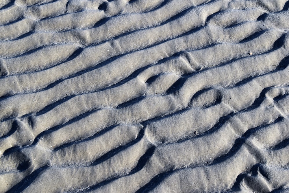 Eine Nahaufnahme eines Sandstrandes mit Fußabdrücken im Sand