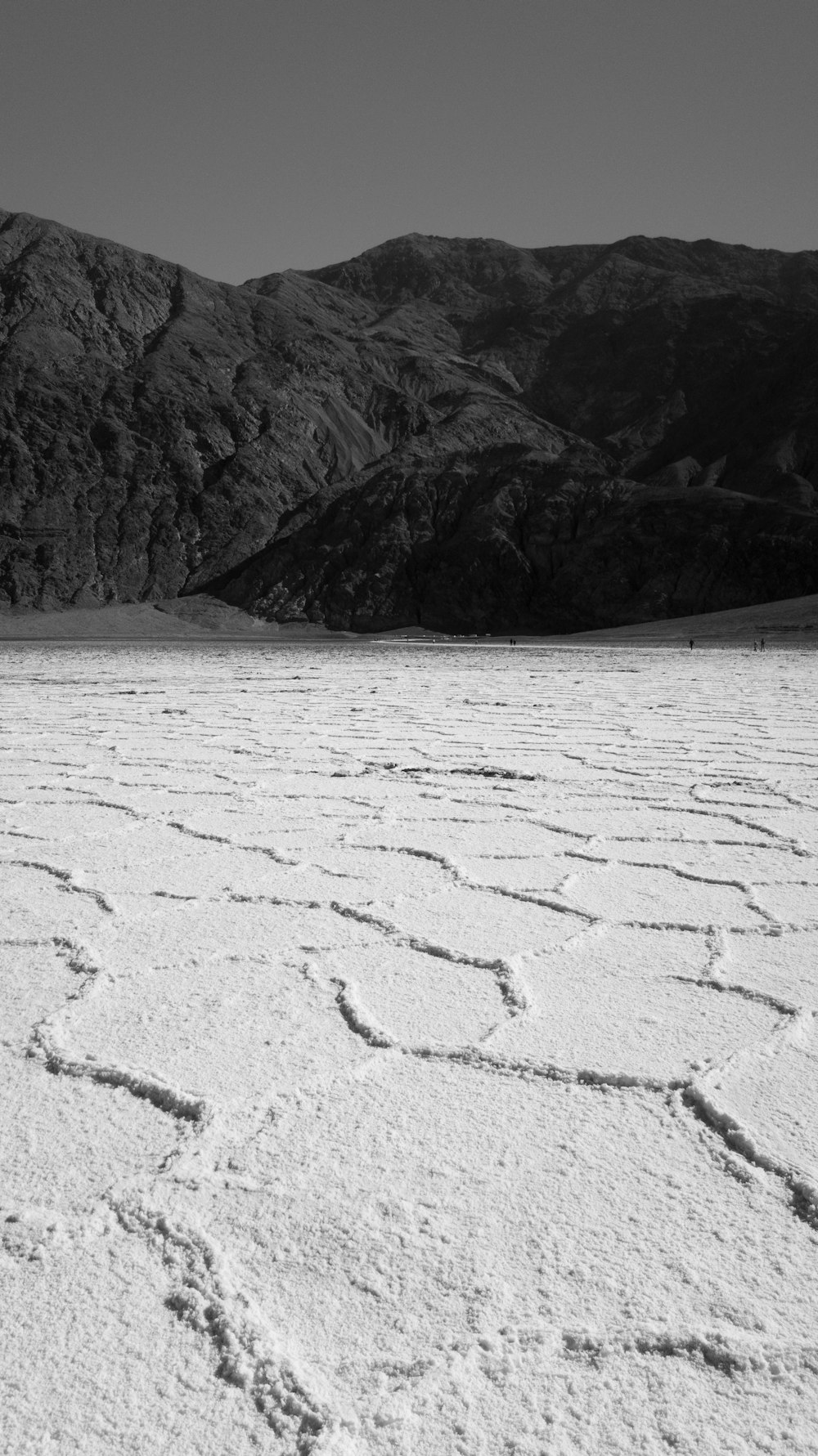 Foto en escala de grises de un cuerpo de agua cubierto de nieve y montañas