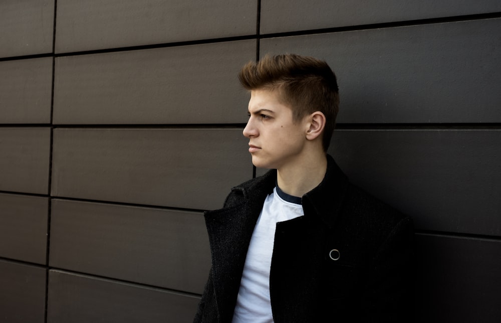 man leaning on gray wall