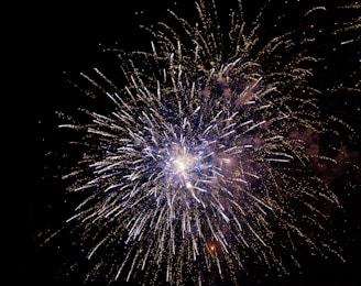 A vibrant burst of golden fireworks illuminating a deep navy blue sky with subtle sparkles.