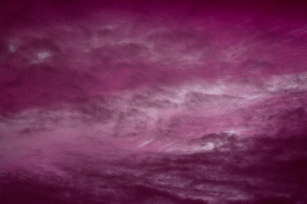 a plane flying through a cloudy blue sky