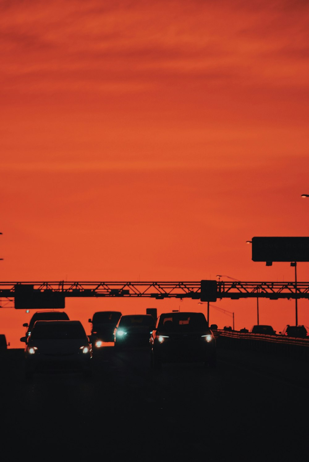 a group of cars driving down a highway under a red sky