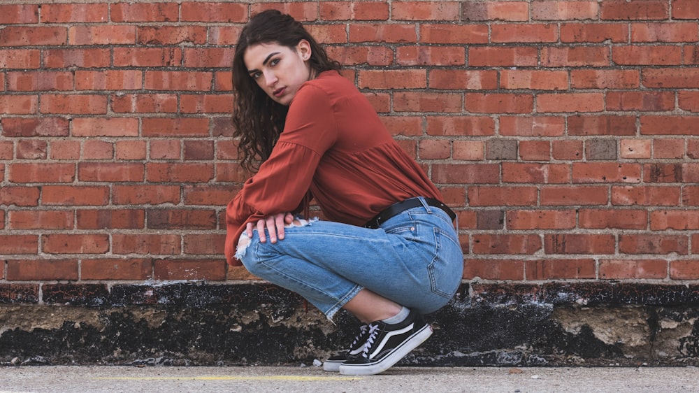 woman sitting beside brick wall