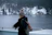 A happy traveler standing on the deck of an expedition ship, wrapped in a warm coat, with icy polar landscapes in the background.