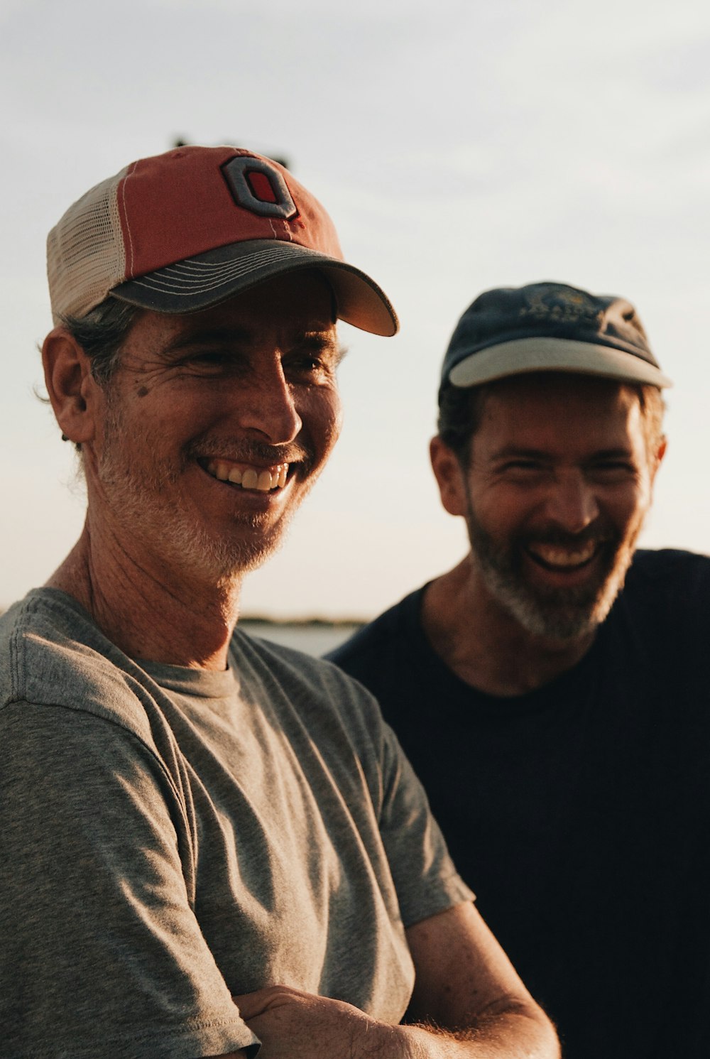 two men wearing baseball caps laughing