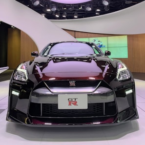 A sleek black sports car displayed in a showroom with bright lights