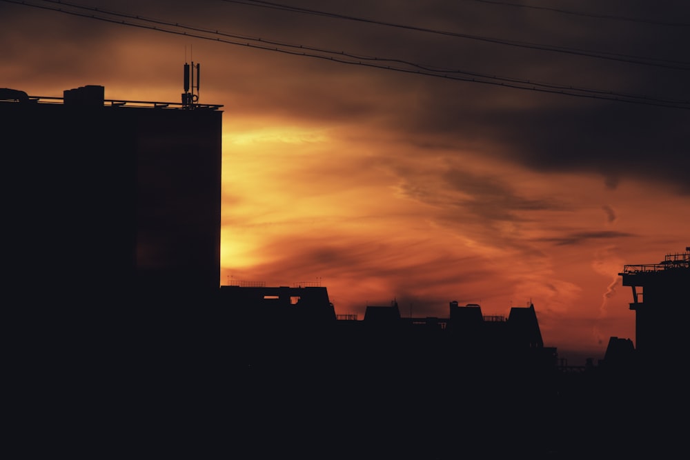 silhouette of houses and buildings under red and orange sky