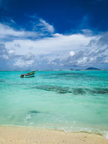A serene morning view of a remote Philippine island with turquoise waters and a small fishing boat near the shore.