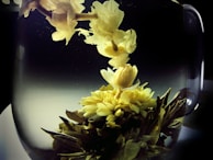 A tea bomb dissolving in a clear glass cup, releasing vibrant floral notes and petals.