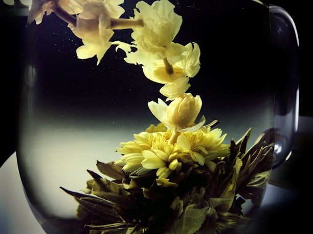 A close-up of vibrant herbal infusion flowers steeping in a clear glass teapot, showcasing natural colors.