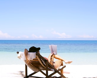 woman sits on brown wooden beach chair