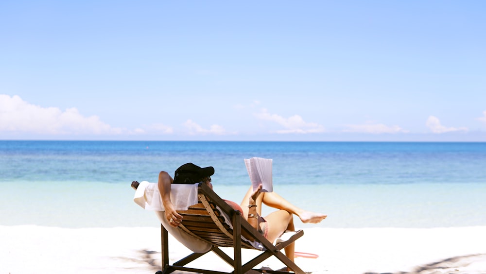 femme s’assoit sur une chaise de plage en bois marron