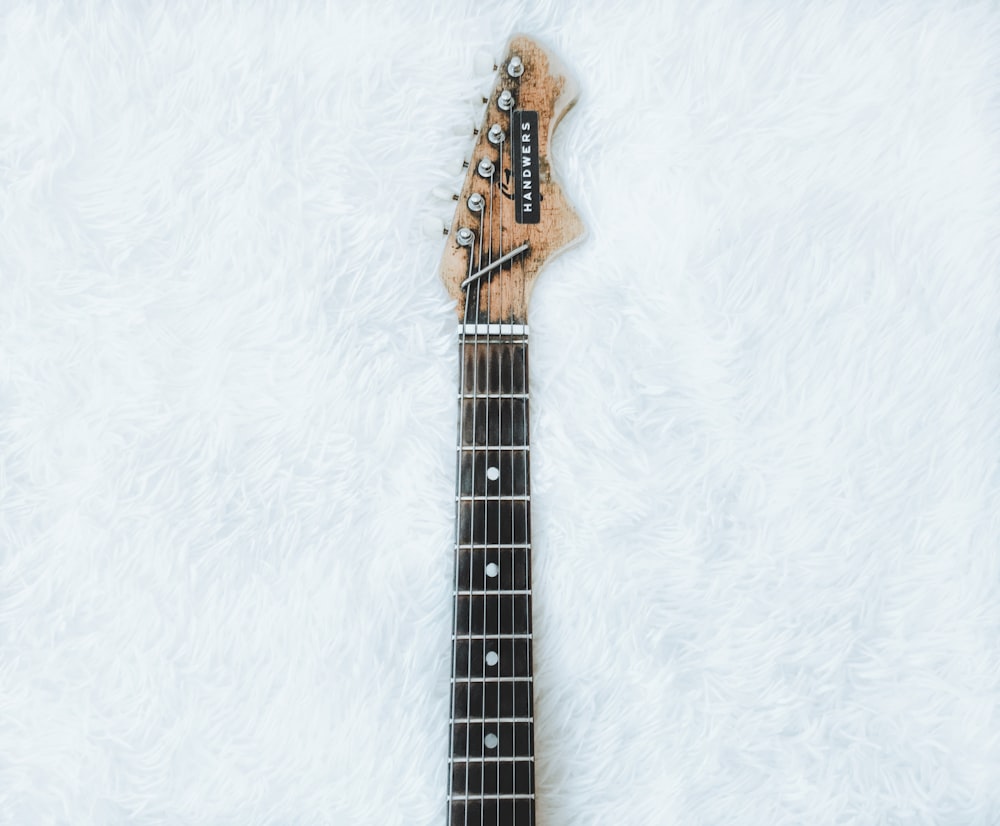 top view of electric guitar neck and headstock on white faux fur