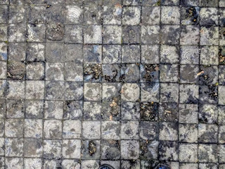 Close-up of textured pavement with shadows from street lamps.