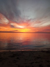 A breathtaking view of Fort Myers Beach at sunset, showing calm waters, sandy shore, and vibrant sky.