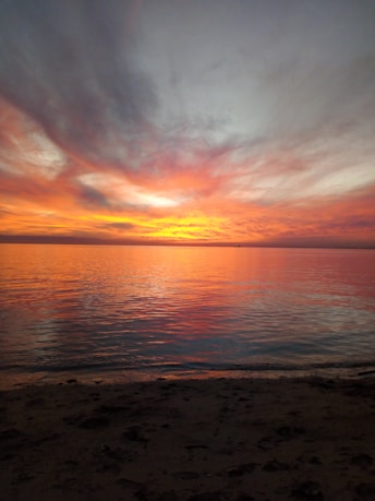 A breathtaking view of Fort Myers Beach at sunset, showing calm waters, sandy shore, and vibrant sky.
