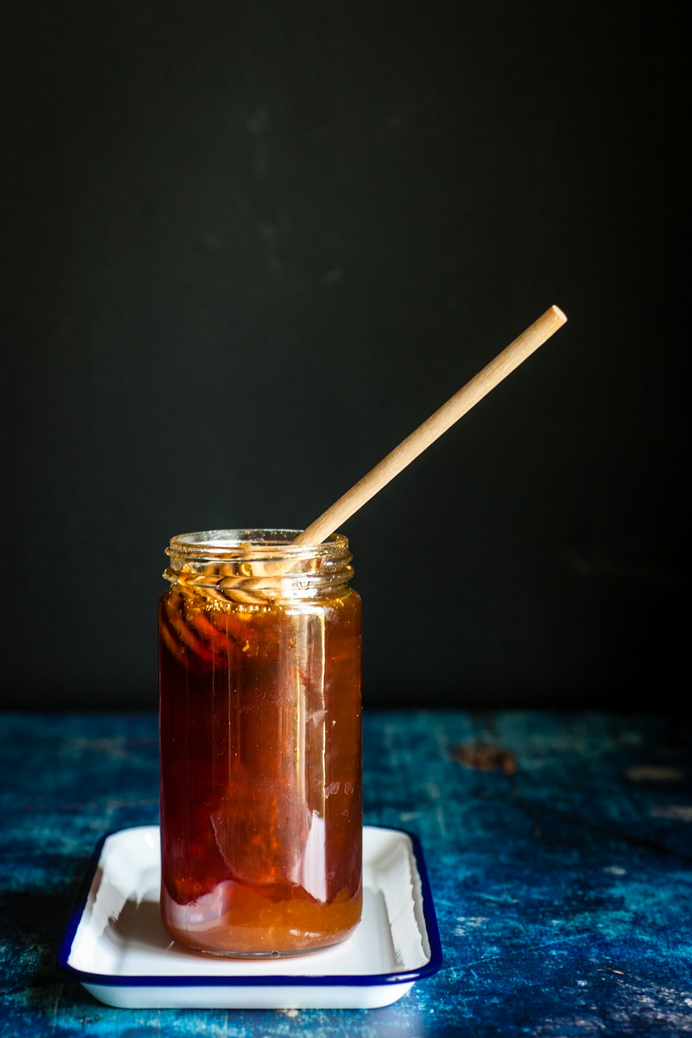brown honey in clear mason jar with stirrer