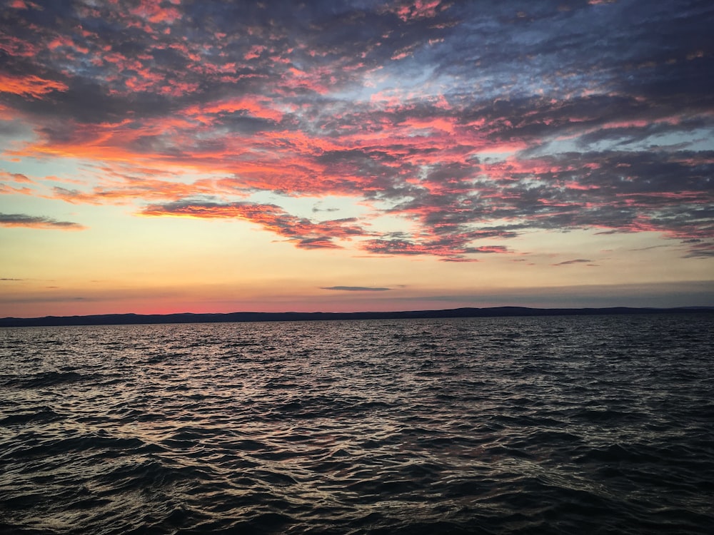 wavy ocean under orange clouds during golden hour