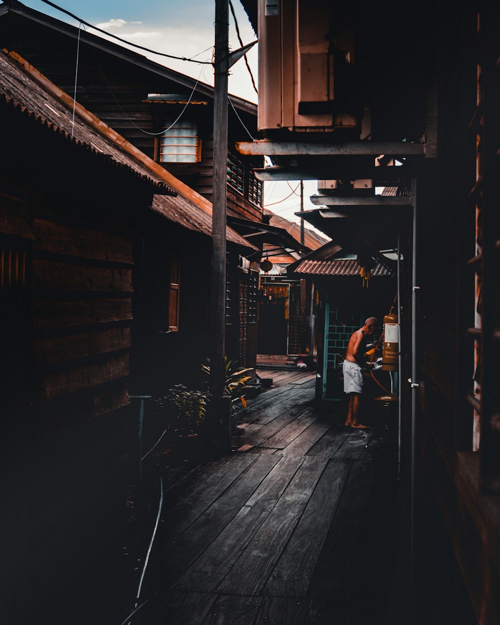 low light photography of man standing beside house