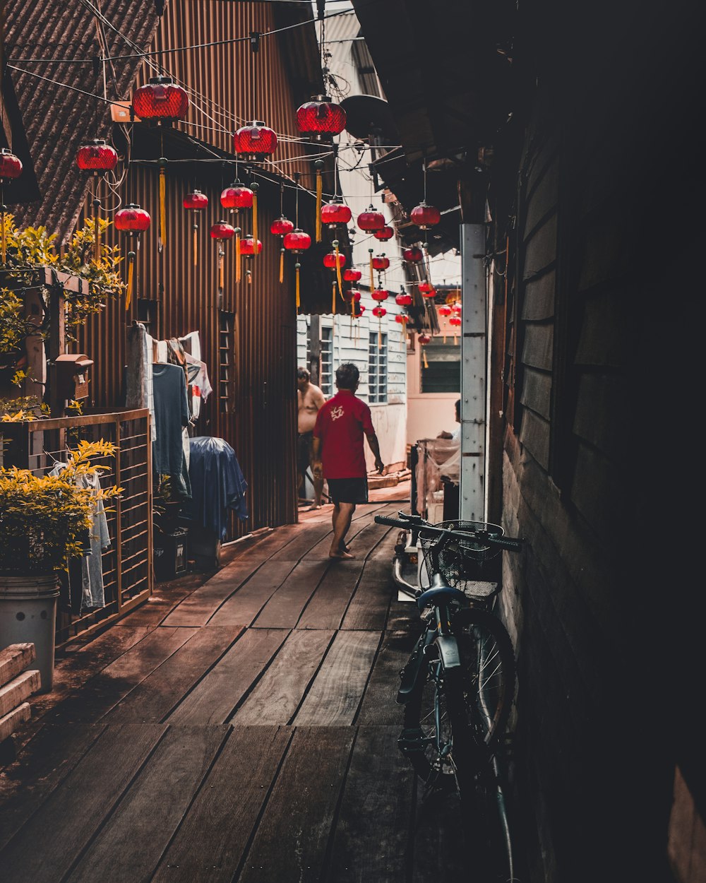 man wearing red shirt walking on brown pathway