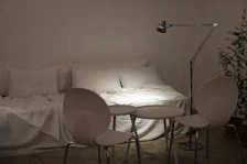 Modern dorm room featuring minimalist decor, a comfortable mattress, and a small bedside lamp.