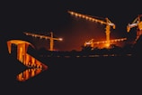 Nighttime shot of illuminated construction cranes at a large civil project.