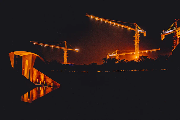 Night view of a lit-up infrastructure project showcasing metal structures and cranes.