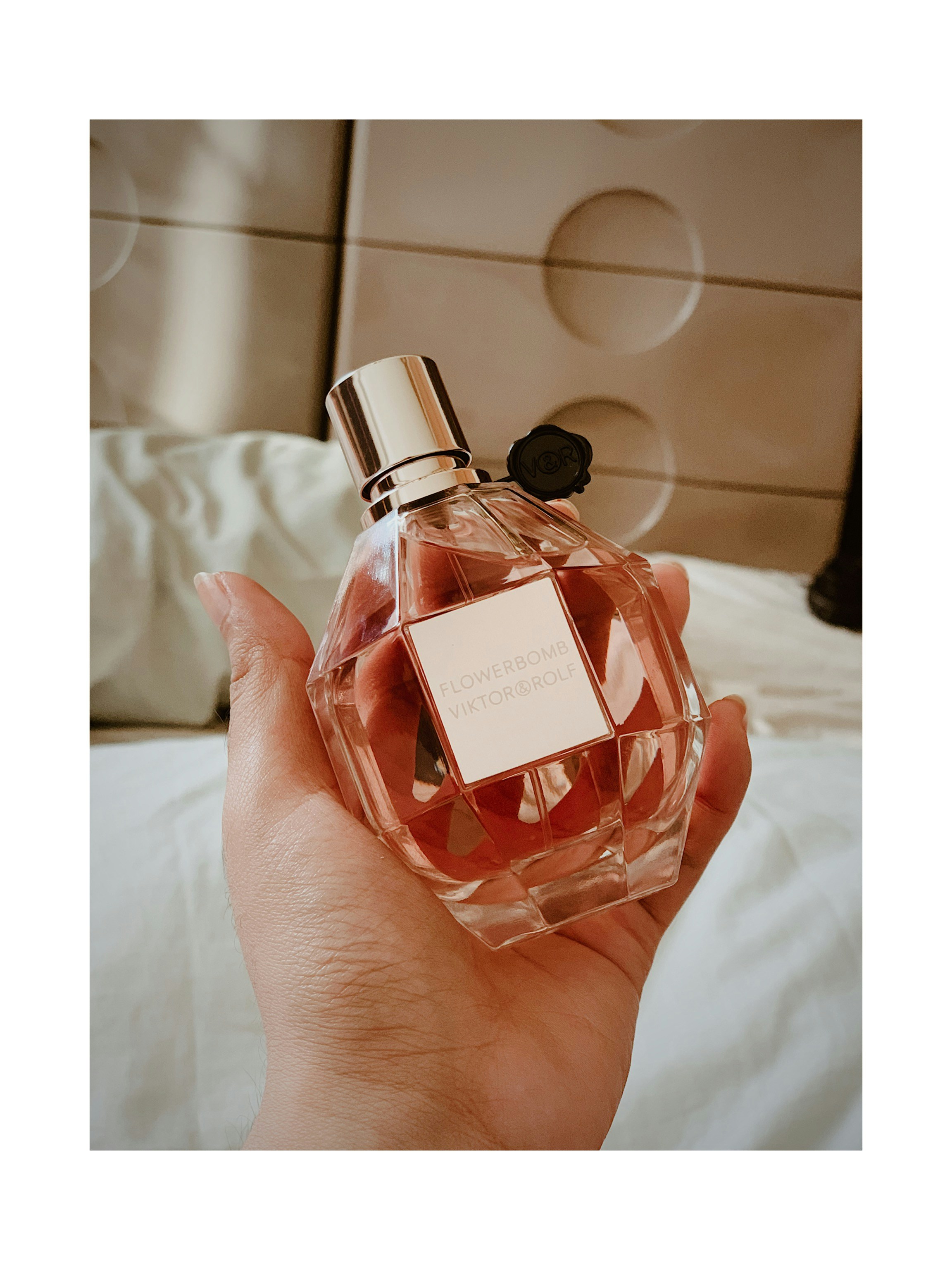 Viktor Rolf Flowerbomb grenade-shaped pink bottle on a floral background with soft feminine lighting