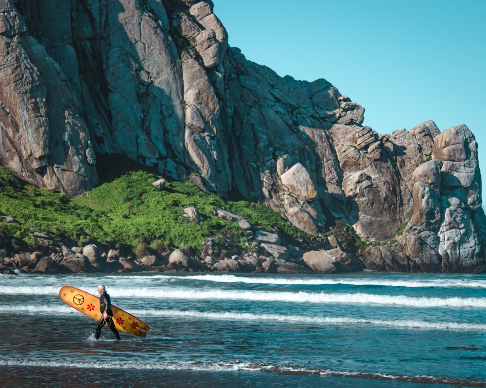 hombre sosteniendo la tabla de surf en el cuerpo de agua