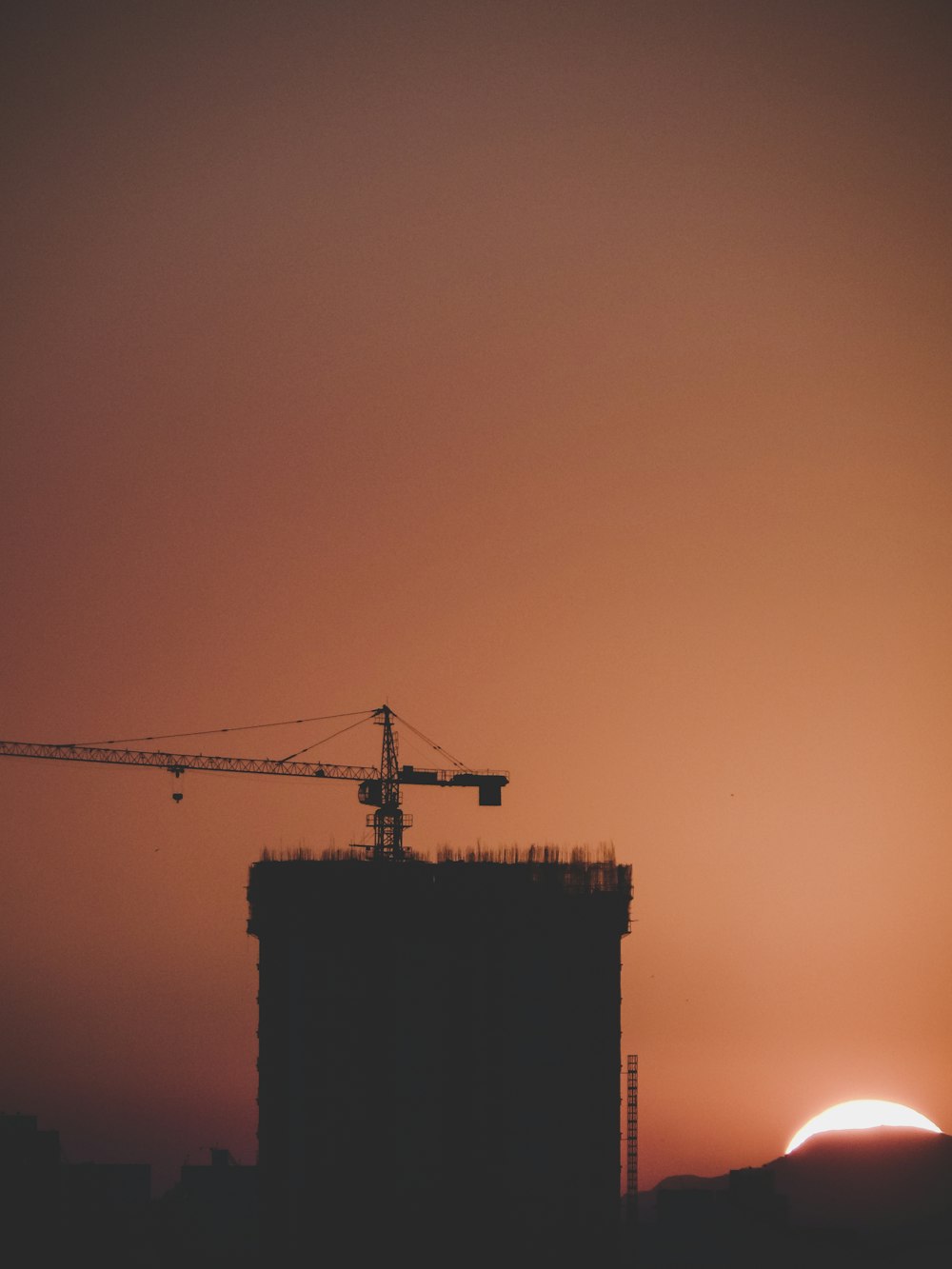 silhouette building and crane during golden hour