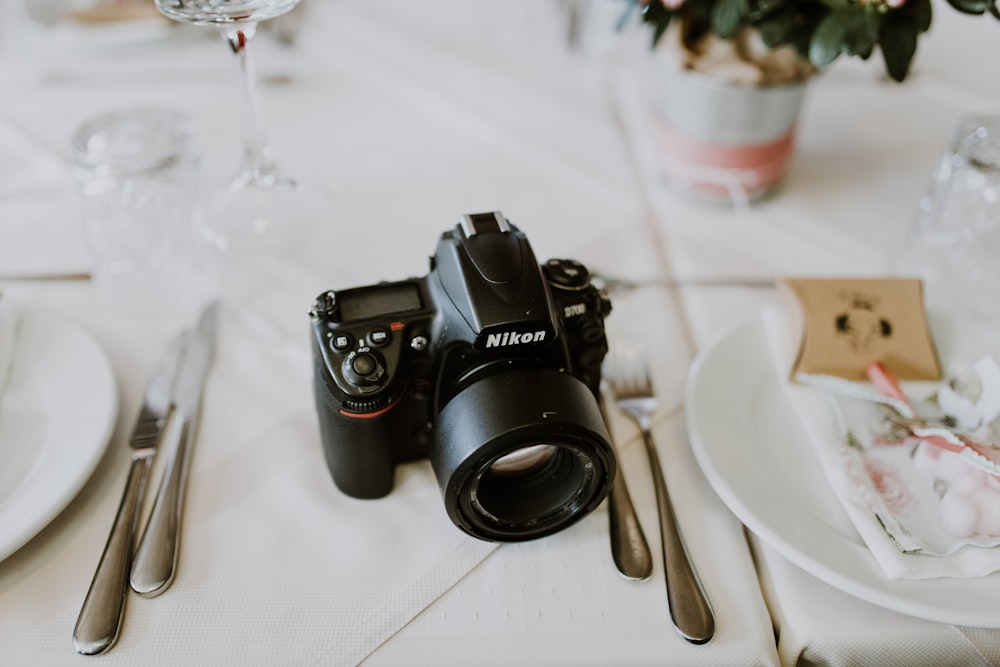 black Nikon camera between plates on table