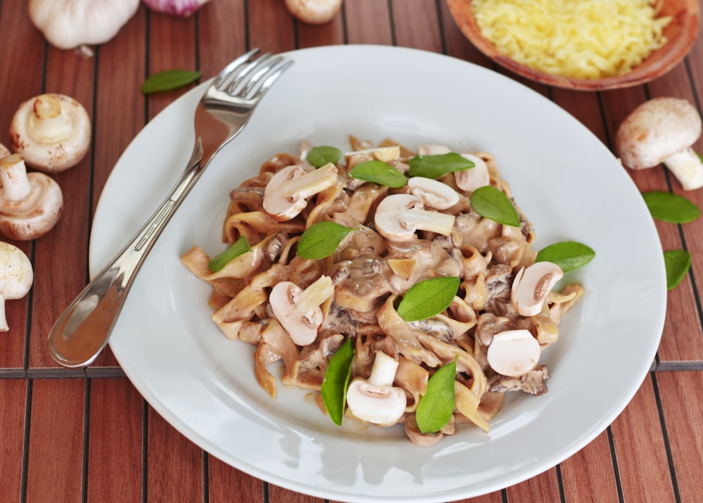 Nudeln mit Champignons mit Blättern auf dem Teller