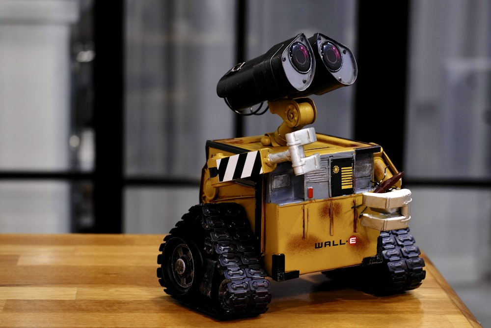 brinquedo Wall-E amarelo e preto na mesa de madeira marrom