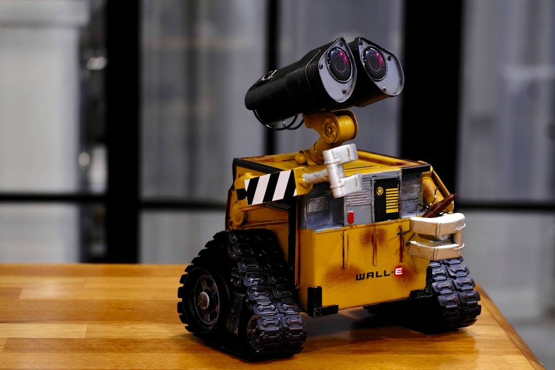 yellow and black Wall-E toy on brown wooden table,