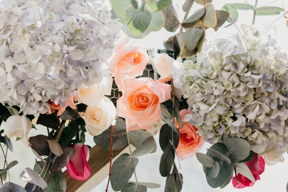 Blumenarrangement mit orangefarbenen, weißen und roten Rosen